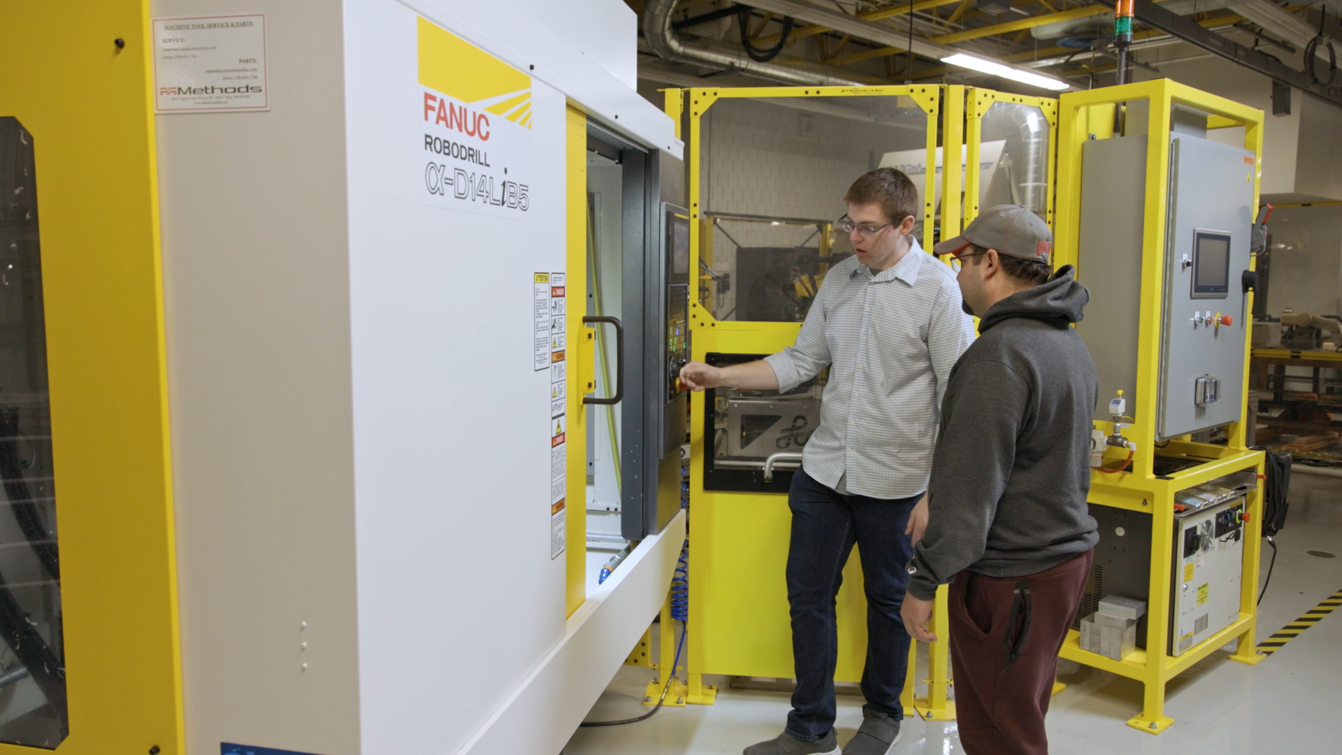 Instructor talking to student while standing next to a FANUC ROBODRILL machine