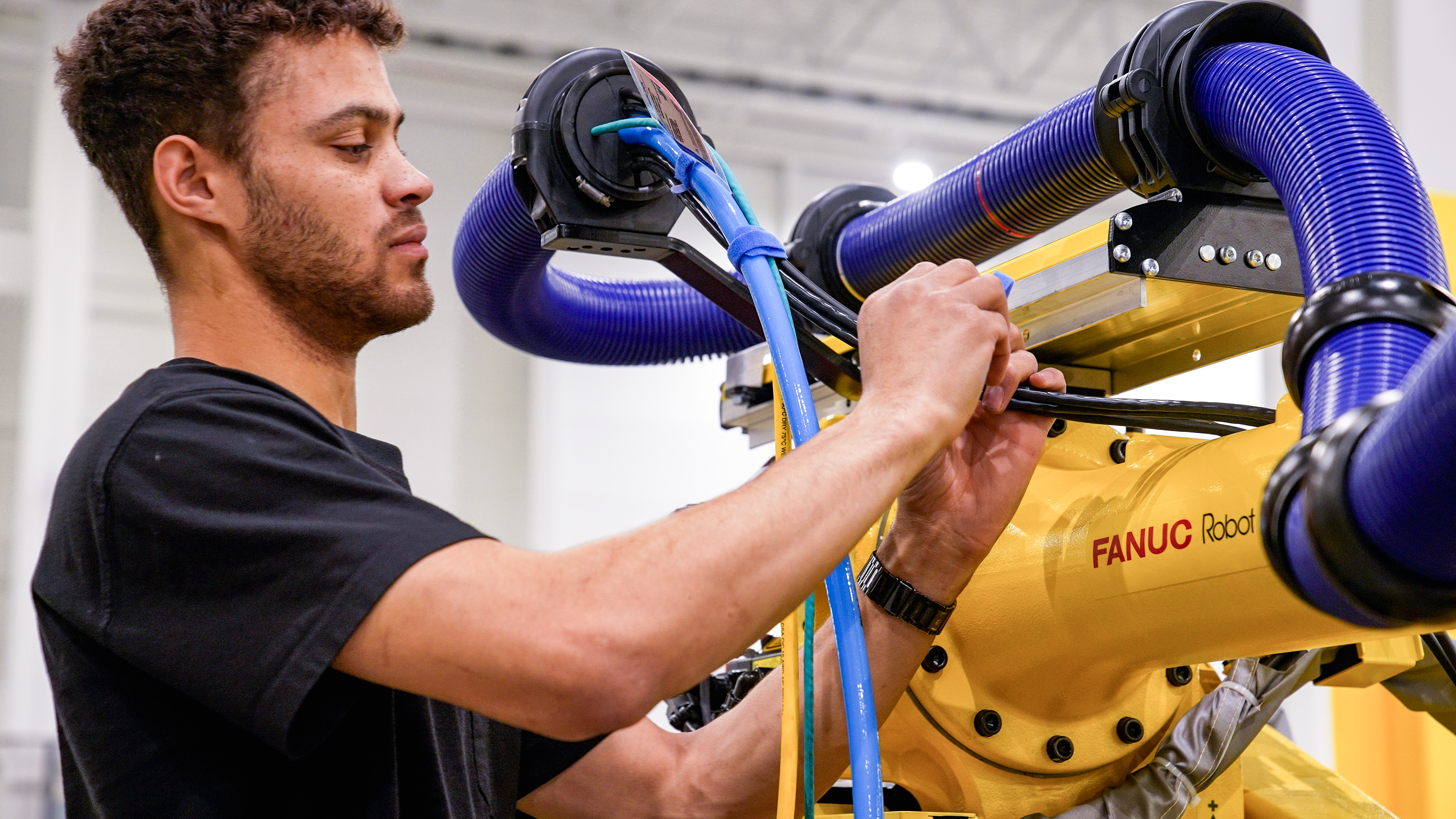 Employee Outfitting Cables on an R 2000 Industrial Robot