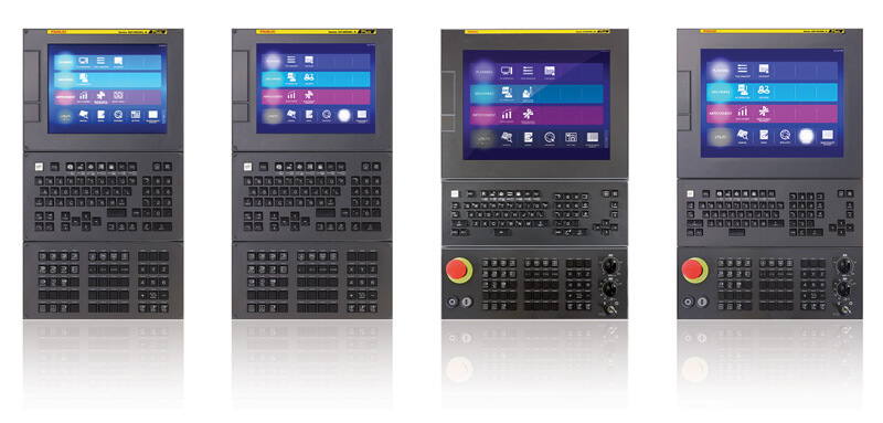 Four industrial CNC control panels side by side, each with a display screen, physical keypad, and numeric buttons; one unit includes a red emergency stop button.